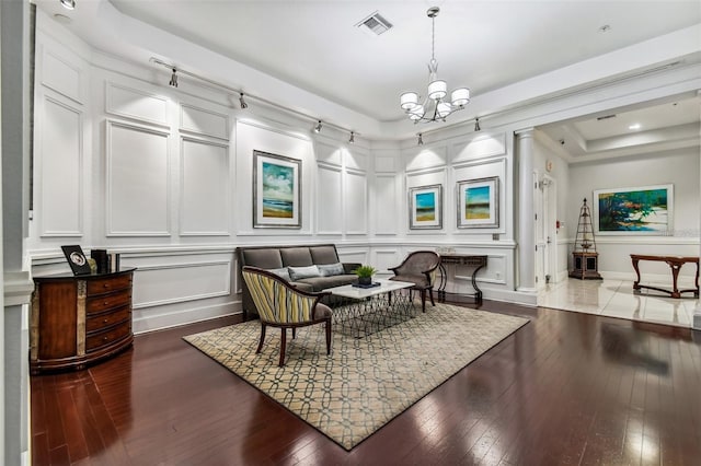 sitting room featuring a decorative wall, a chandelier, hardwood / wood-style floors, and baseboards