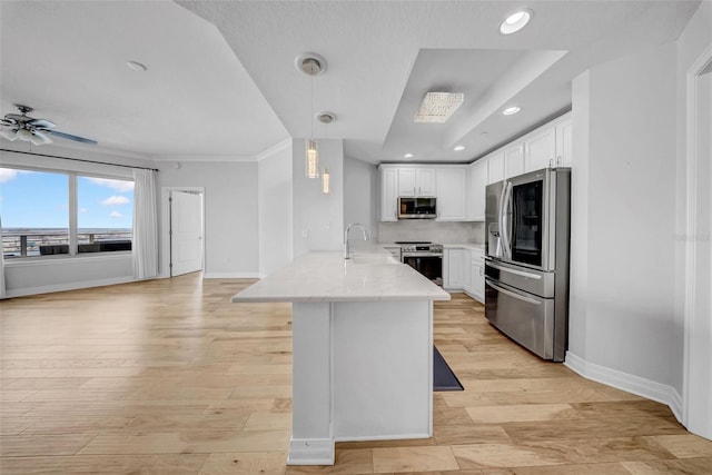 kitchen with baseboards, a sink, white cabinetry, a peninsula, and appliances with stainless steel finishes