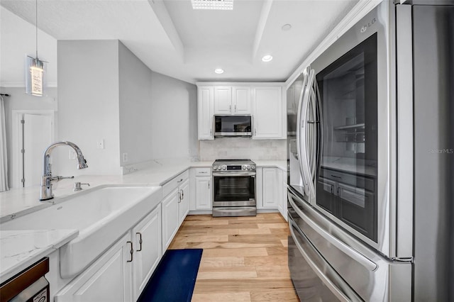 kitchen featuring a sink, stainless steel appliances, white cabinetry, light wood-style floors, and recessed lighting