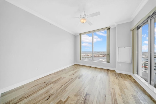 spare room featuring light wood-type flooring, baseboards, a ceiling fan, and ornamental molding