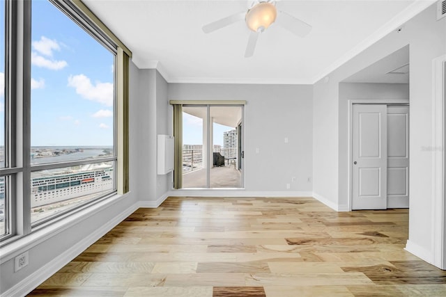 spare room featuring light wood finished floors, ornamental molding, and baseboards