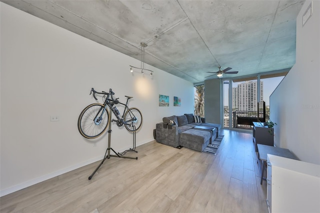 living room featuring baseboards, light wood-style floors, ceiling fan, and floor to ceiling windows