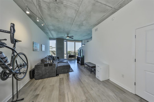living area with visible vents, a ceiling fan, floor to ceiling windows, baseboards, and light wood-style floors