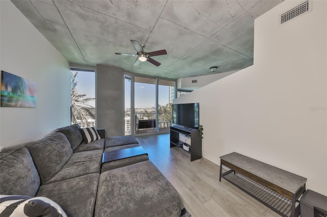 living room with ceiling fan, light wood-style flooring, visible vents, and floor to ceiling windows