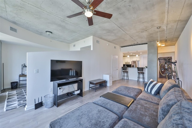 living area featuring baseboards, ceiling fan, light wood finished floors, and visible vents
