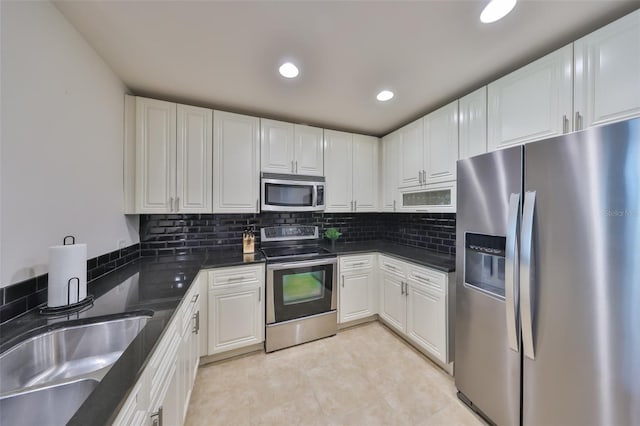 kitchen featuring white cabinetry, stainless steel appliances, tasteful backsplash, and a sink