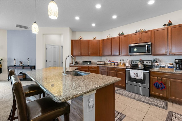 10626 Laguna Plains Dr, Riverview, FL 33578 - kitchen with appliances with stainless steel finishes, a sink, a kitchen bar, hanging light fixtures, and an island with sink
