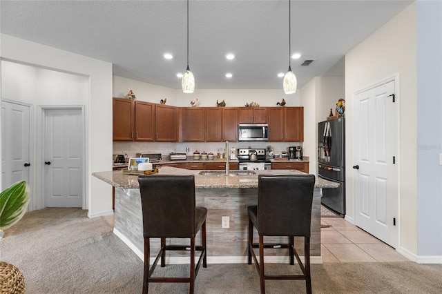 10626 Laguna Plains Dr, Riverview, FL 33578 - kitchen featuring stainless steel appliances, a sink, light carpet, brown cabinetry, and a kitchen bar