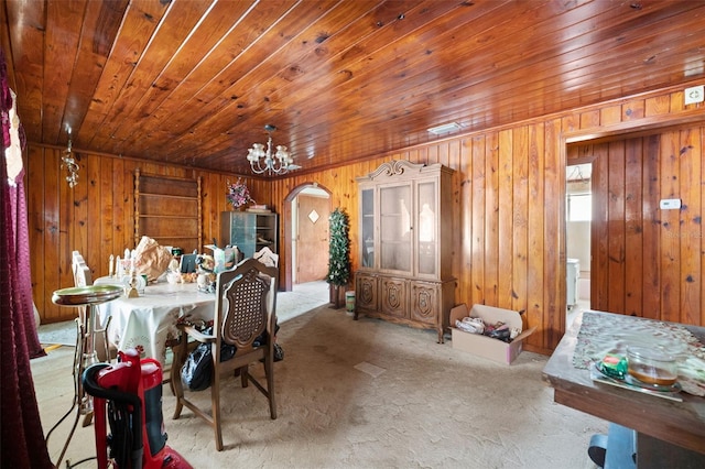 carpeted dining area with arched walkways, wooden walls, a chandelier, and wooden ceiling