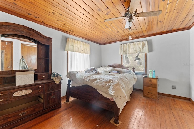 bedroom with ceiling fan, crown molding, baseboards, and wood-type flooring