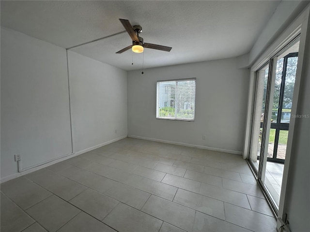 empty room featuring a ceiling fan, baseboards, light tile patterned flooring, and a textured ceiling