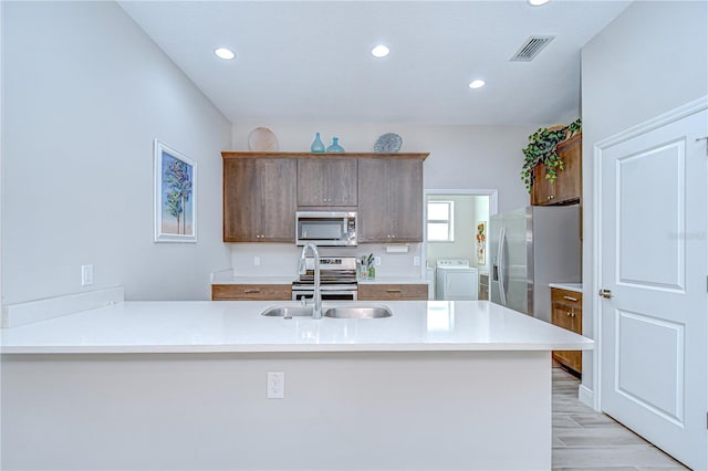 5732 Stockport St, Riverview, FL 33578 - kitchen featuring a peninsula, a sink, visible vents, washer / dryer, and appliances with stainless steel finishes