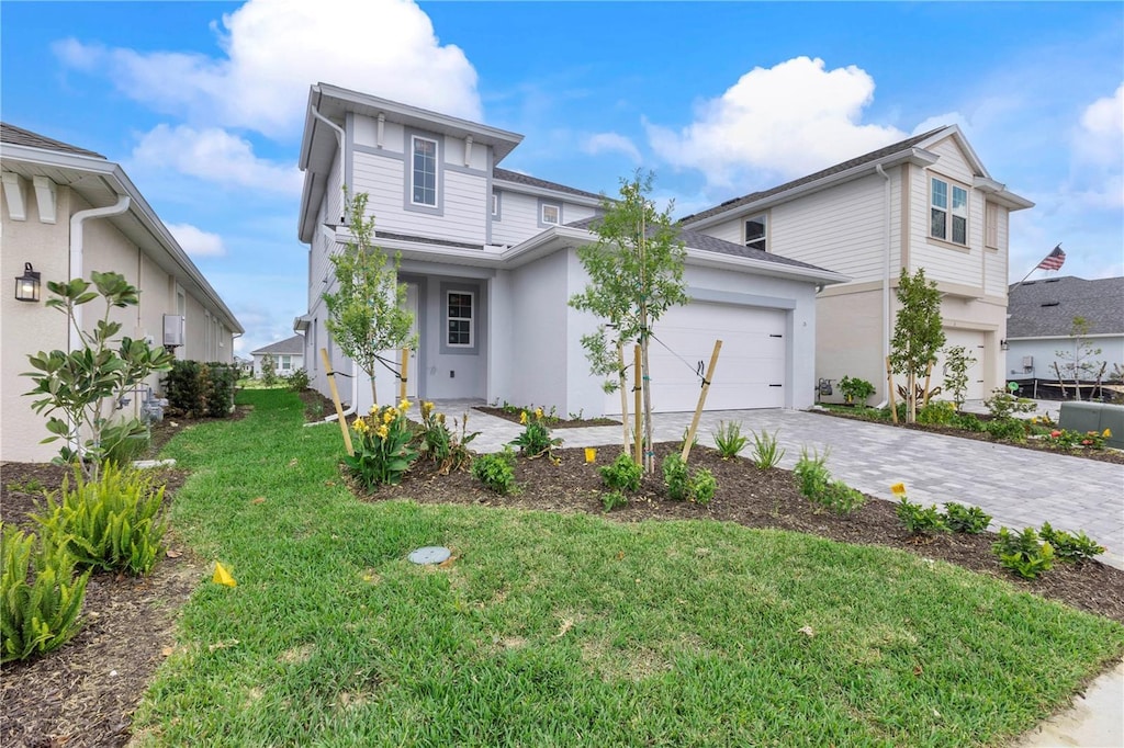 view of front facade featuring an attached garage, stucco siding, decorative driveway, and a front yard