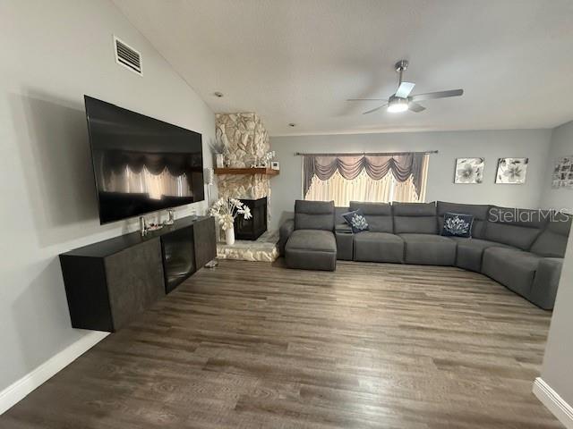 1710 Tallowtree Cir, Valrico, FL 33594 - living room featuring wood finished floors, visible vents, a ceiling fan, baseboards, and a stone fireplace
