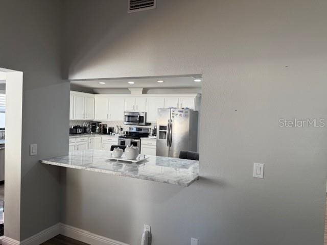 1710 Tallowtree Cir, Valrico, FL 33594 - kitchen featuring a peninsula, white cabinets, visible vents, and appliances with stainless steel finishes
