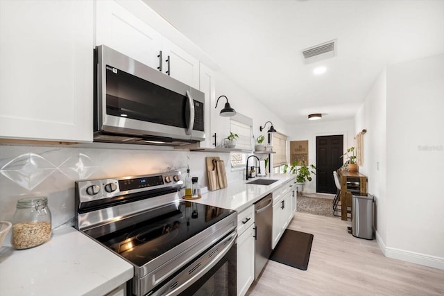 14 S Meteor Ave, Clearwater, FL 33765 - kitchen featuring stainless steel appliances, a sink, open shelves, white cabinets, and light wood-style floors