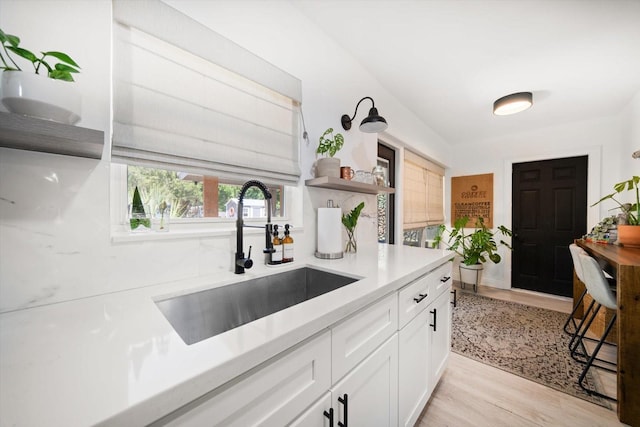 14 S Meteor Ave, Clearwater, FL 33765 - kitchen with a sink, open shelves, light wood-style floors, white cabinetry, and light countertops