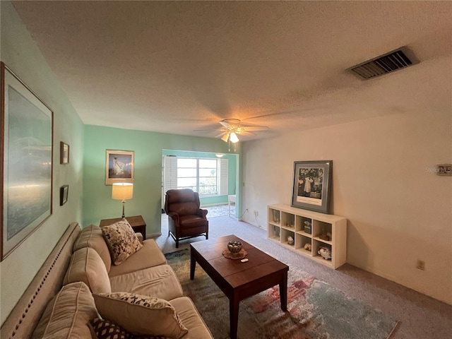 carpeted living area with a textured ceiling and a ceiling fan