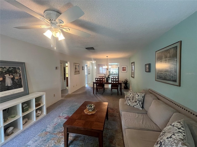 carpeted living room with a textured ceiling, a ceiling fan, and a chandelier