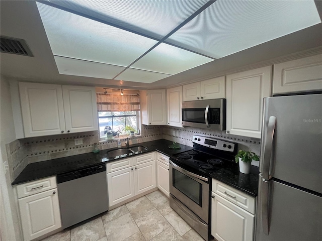 kitchen with appliances with stainless steel finishes, a sink, tasteful backsplash, and white cabinets