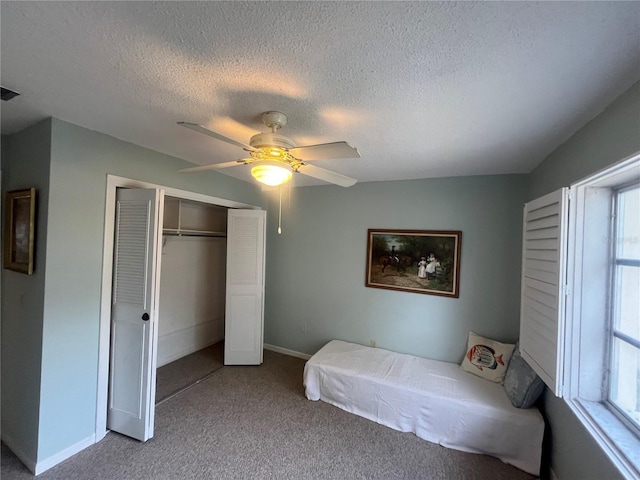 bedroom featuring carpet, a textured ceiling, a closet, baseboards, and a ceiling fan