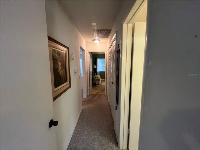 hallway featuring carpet and baseboards