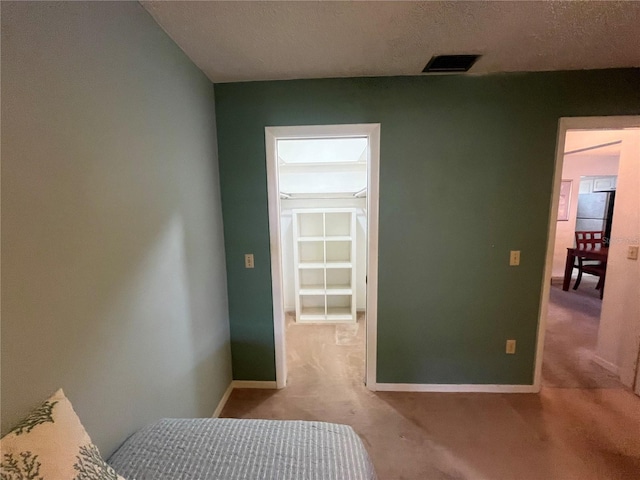 carpeted bedroom with baseboards, a spacious closet, and freestanding refrigerator