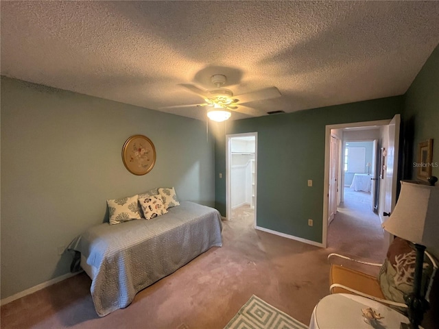 carpeted bedroom featuring baseboards, ceiling fan, a textured ceiling, and a spacious closet