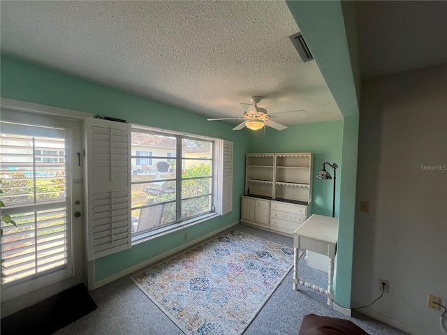 unfurnished room with ceiling fan, a textured ceiling, baseboards, and carpet floors