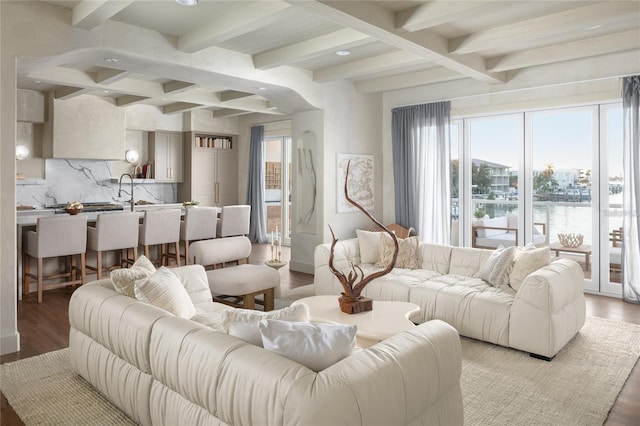 living area featuring coffered ceiling, a water view, light wood-type flooring, and beam ceiling