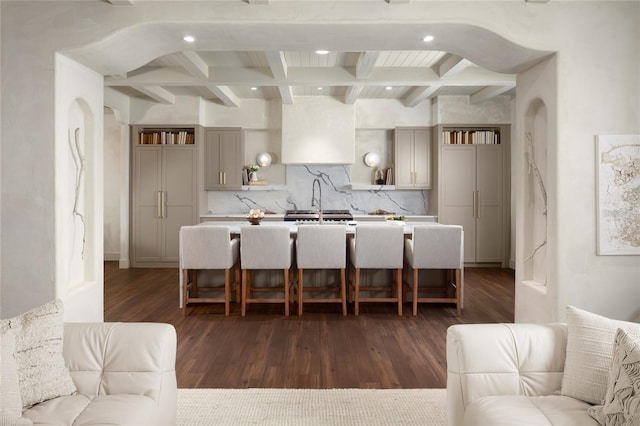 kitchen featuring open shelves, a kitchen island with sink, beam ceiling, and tasteful backsplash