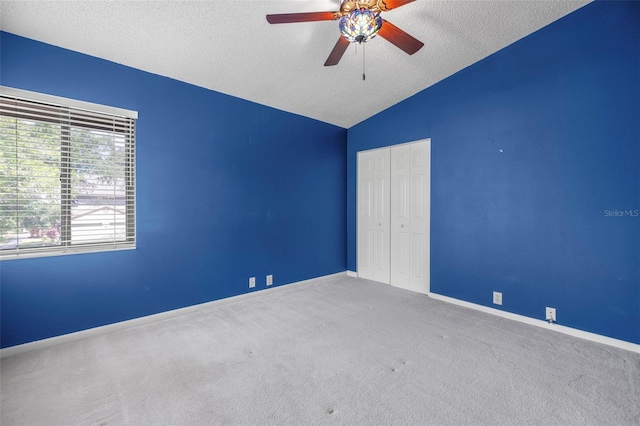 3066 Landmark Blvd Unit 1305, Palm Harbor, FL 34684 - unfurnished bedroom featuring a closet, carpet flooring, a textured ceiling, lofted ceiling, and baseboards