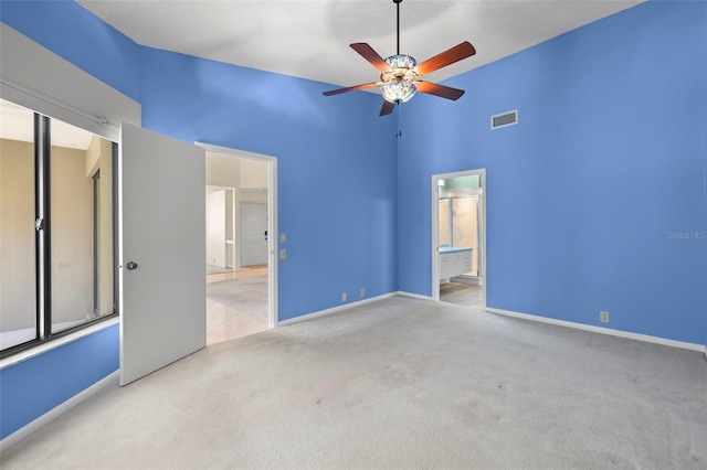 3066 Landmark Blvd Unit 1305, Palm Harbor, FL 34684 - unfurnished bedroom with carpet flooring, baseboards, ensuite bath, ceiling fan, and a towering ceiling