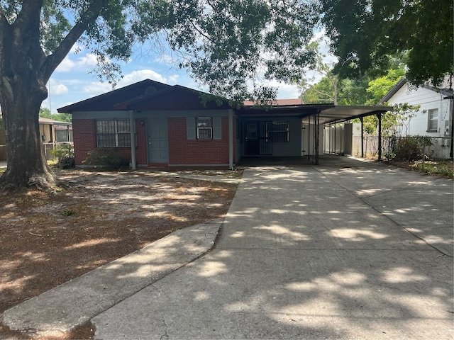 single story home with fence, concrete driveway, brick siding, and an attached carport