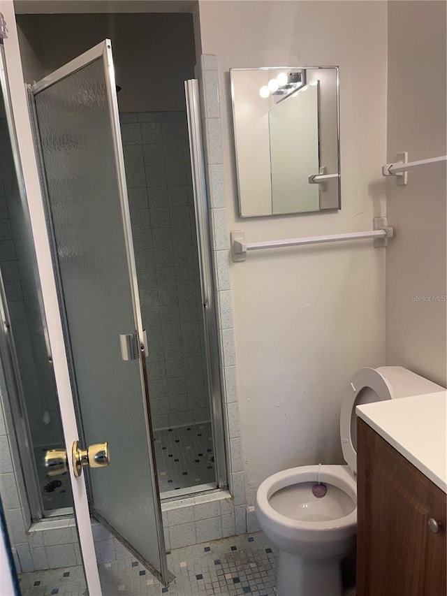 full bathroom featuring a shower stall, toilet, and vanity