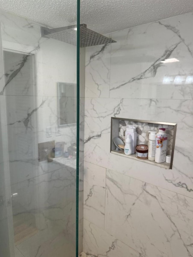 full bath featuring a marble finish shower and a textured ceiling