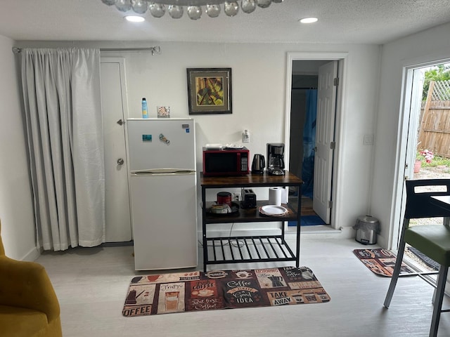 interior space featuring freestanding refrigerator, a textured ceiling, wood finished floors, and recessed lighting