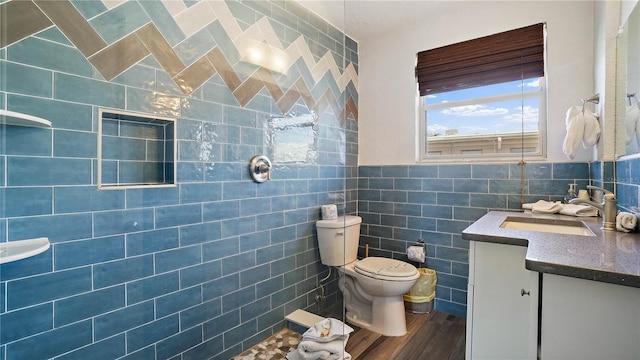 bathroom with toilet, tile walls, vanity, and wood finished floors