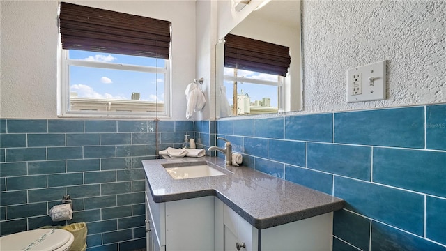 bathroom with a wainscoted wall, vanity, tile walls, and toilet