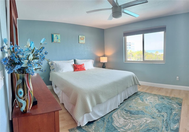 bedroom with baseboards, a ceiling fan, and light wood-style floors