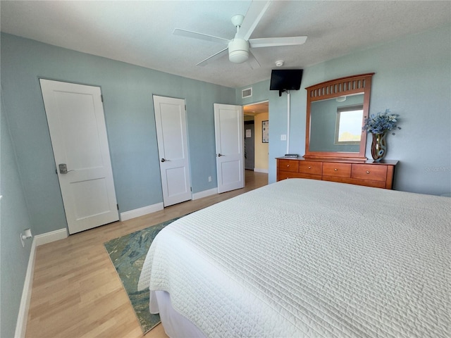bedroom featuring light wood finished floors, baseboards, a ceiling fan, and visible vents