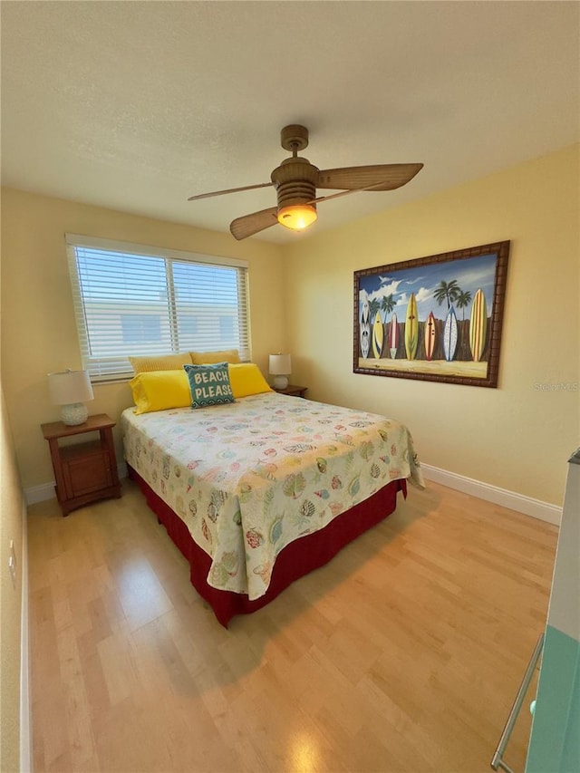 bedroom featuring baseboards, light wood-style flooring, and ceiling fan