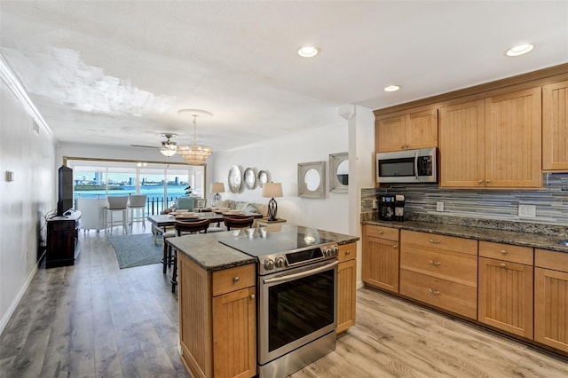 kitchen with appliances with stainless steel finishes, ornamental molding, decorative backsplash, light wood-style floors, and a ceiling fan