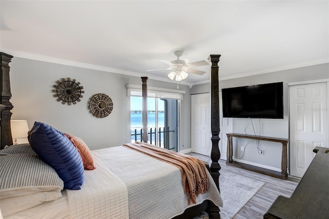 bedroom with wood finished floors, crown molding, a ceiling fan, baseboards, and multiple closets