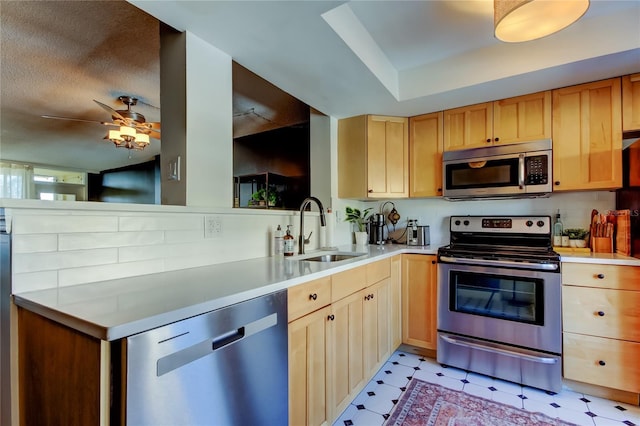 kitchen with appliances with stainless steel finishes, a sink, light floors, light countertops, and a ceiling fan