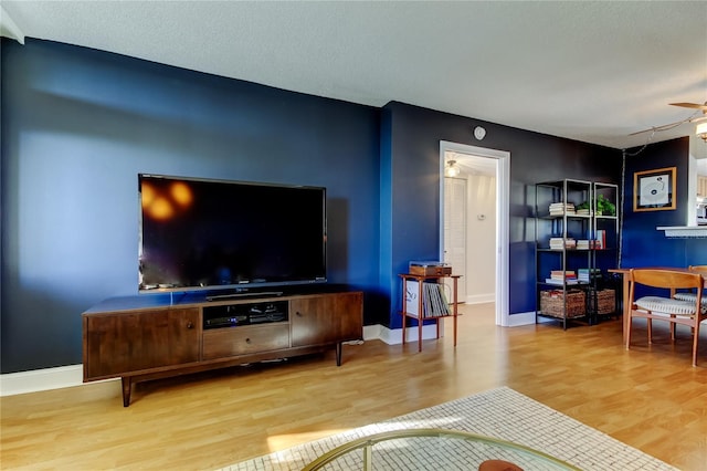 living room with wood finished floors, a ceiling fan, and baseboards