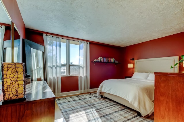 bedroom with a textured ceiling, baseboards, and wood finished floors