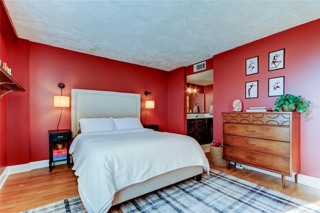 bedroom featuring wood finished floors, baseboards, and a textured ceiling