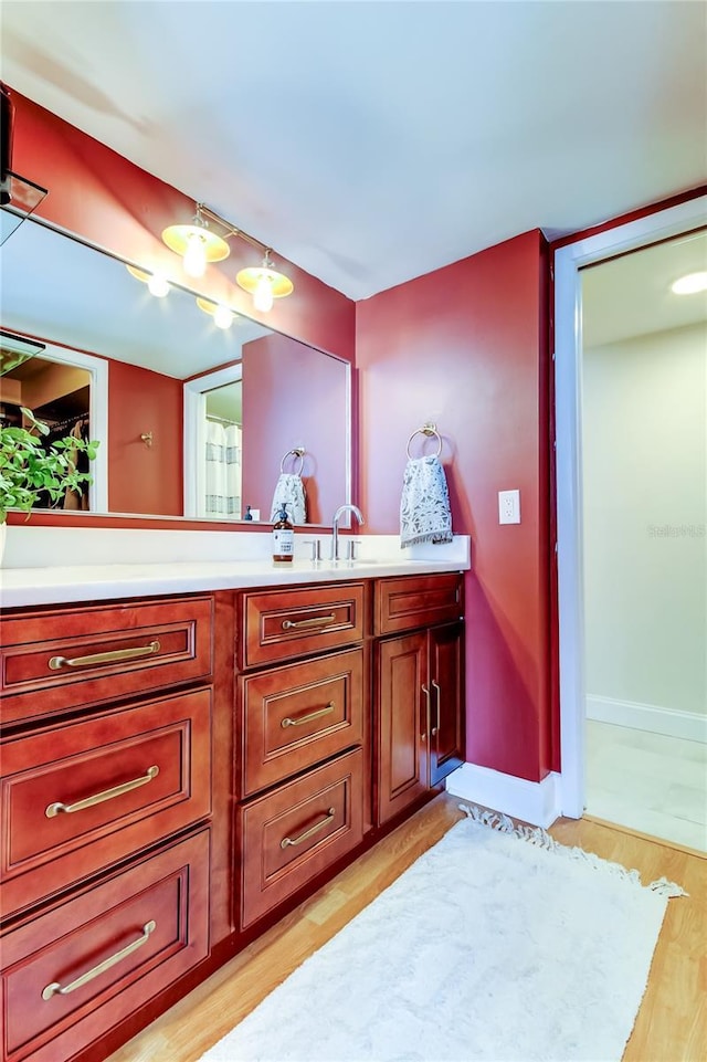 full bath featuring wood finished floors, vanity, and baseboards