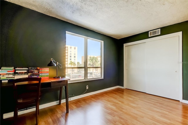 office area with wood finished floors, a textured ceiling, and baseboards